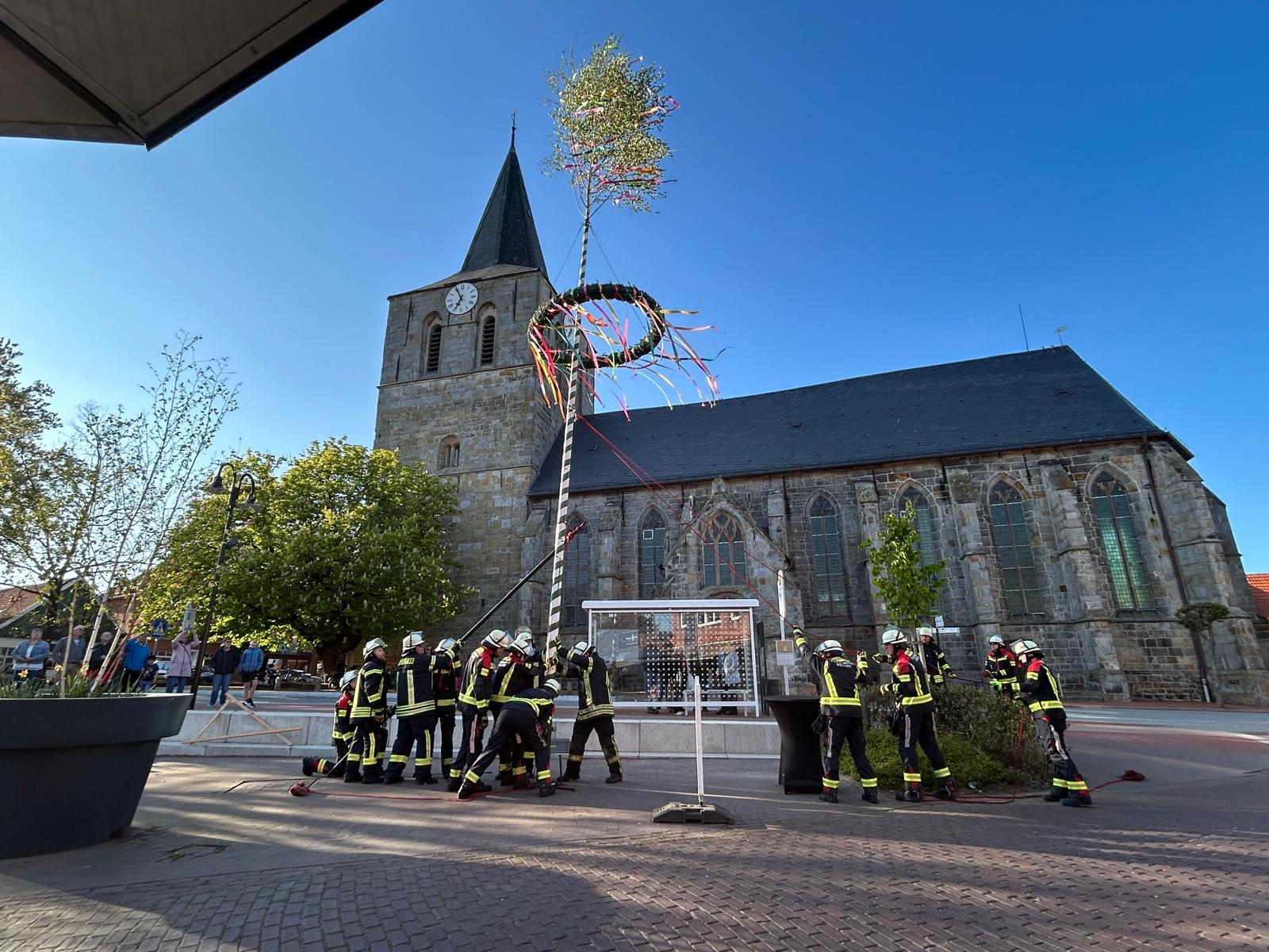 Maypole erection 2026 - the maypole is standing, church in the background