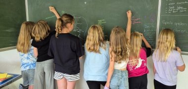 Children write on a blackboard