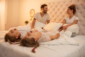 Dos hermanas pequeñas gritando en la cama de sus padres.