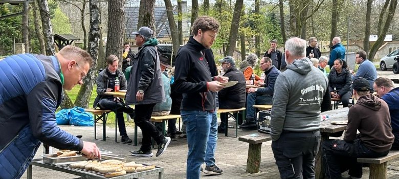Die Helfer sitzen nach der Arbeit zusammen am Grillplatz