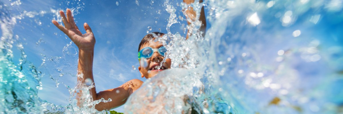 Happy boy playing and splashing in swimming pool